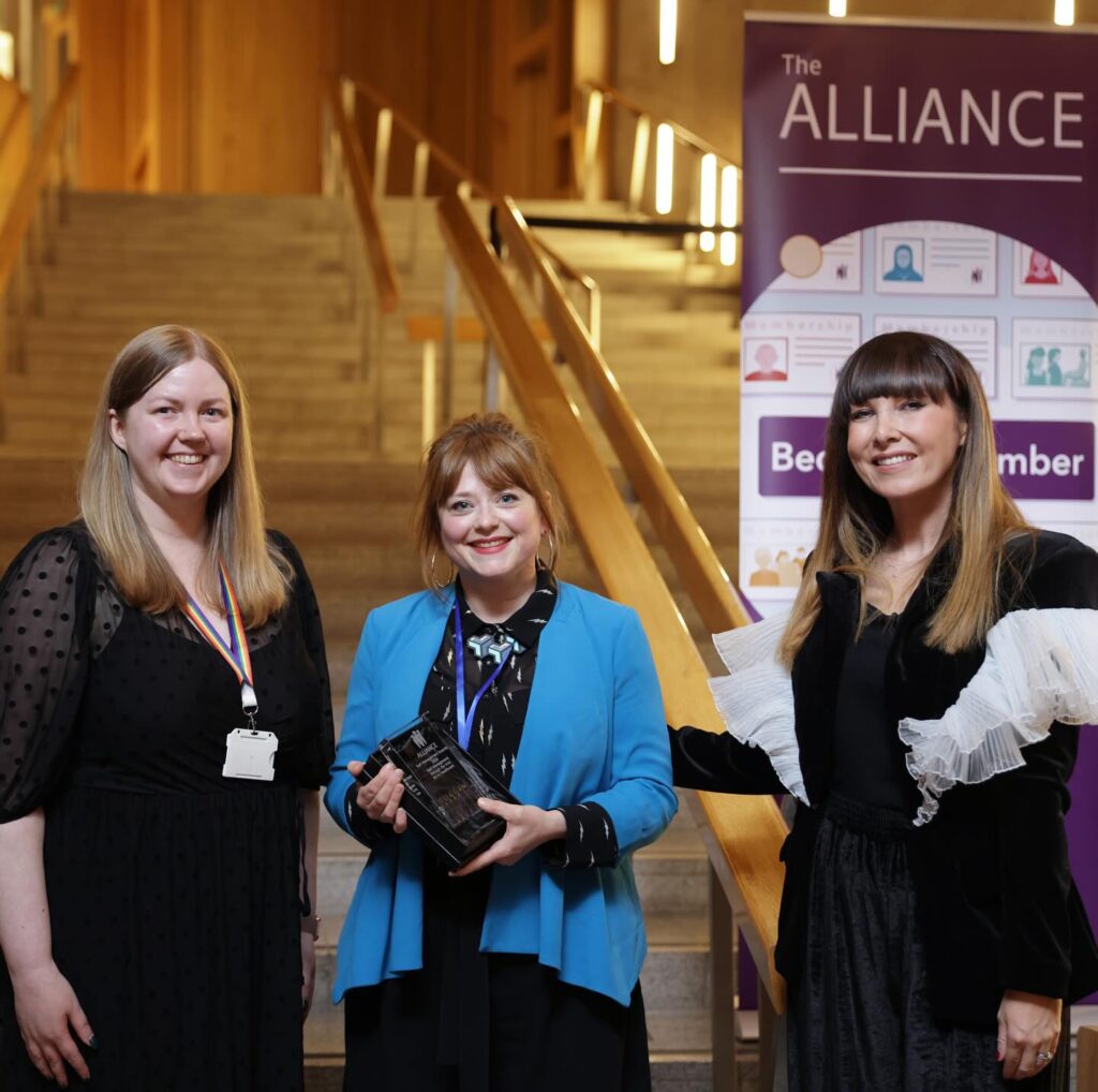 Our Associate Director (Communities) holding the award at the Scottish Parliament.